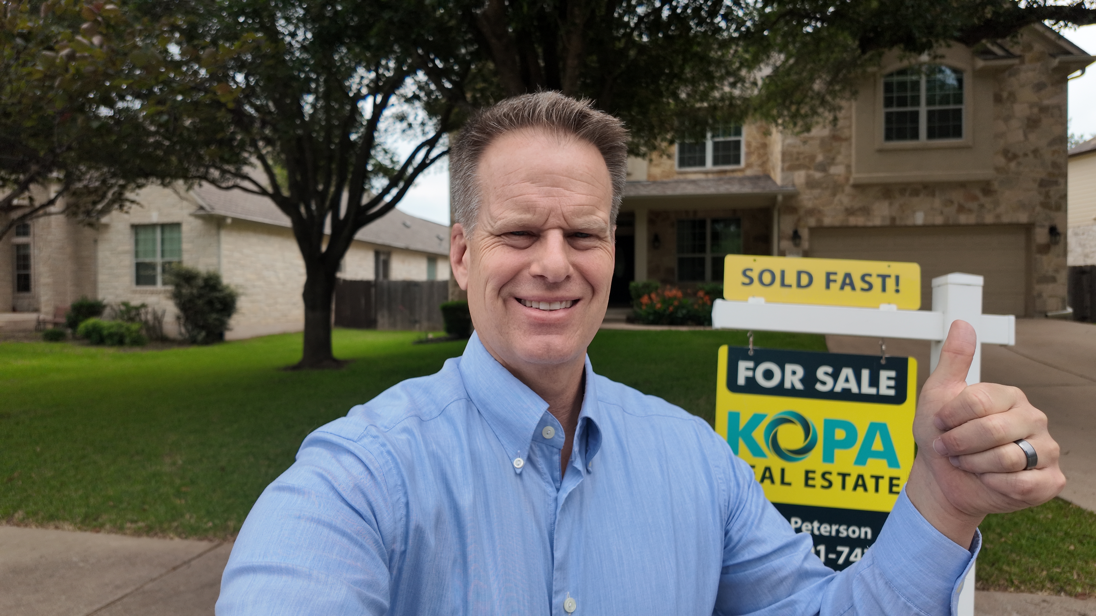 Eric in front of one our most recent sold homes holding a thumbs up.